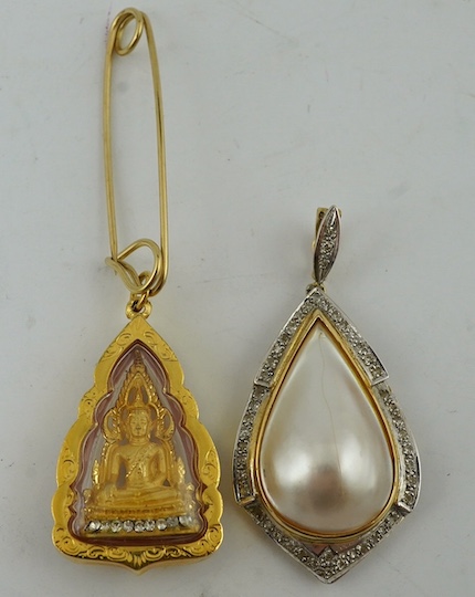 A modern yellow metal, mother of pearl and diamond chip set pear shaped pendant, overall 43mm, together with an Indian? yellow metal pendant, inset with figure. Condition - fair